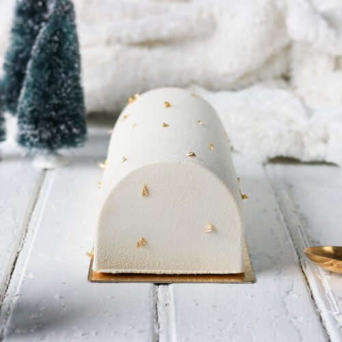 Une bûche à la vanille floquée en blanc et décorée avec des feuilles d'or