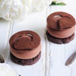 Deux petites tartelettes au chocolat composées d'un sablé reconstitué, d'une bavaroise au chocolat et d'un décor en pâte sucrée au cacao