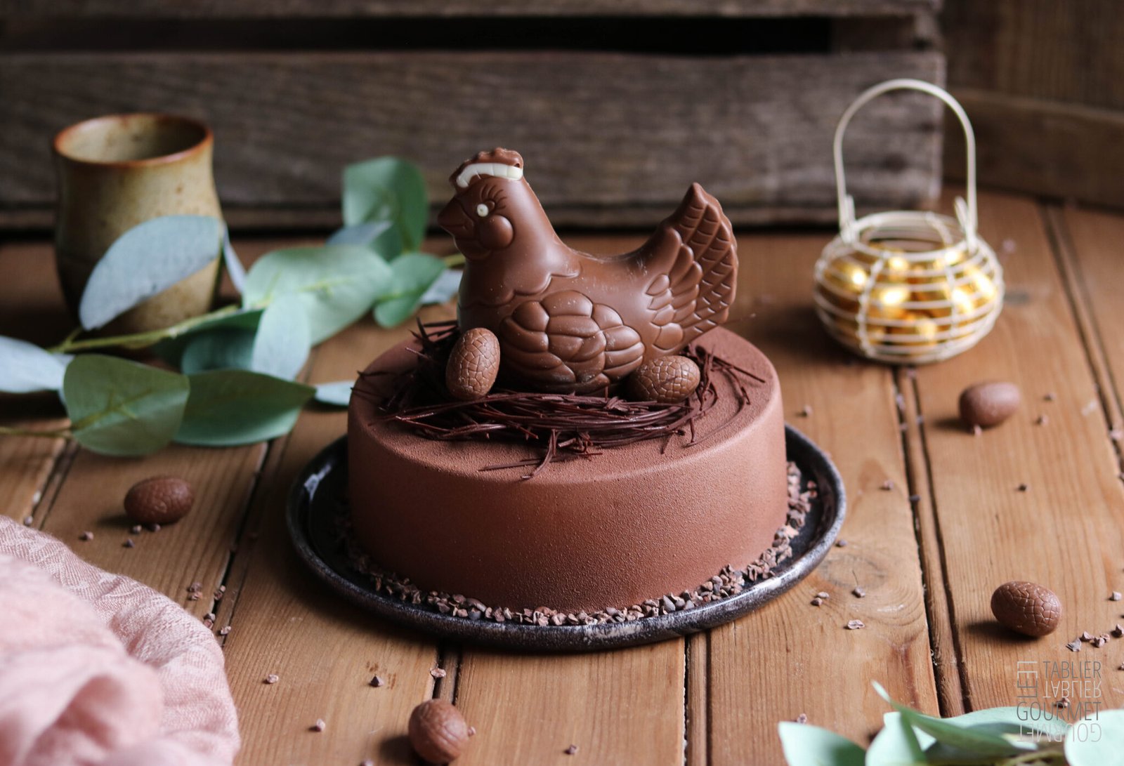 L'entremets de Pâques au chocolat et caramel est surmonté d'un nid en chocolat et d'une figurine aussi en chocolat, en forme de poulette