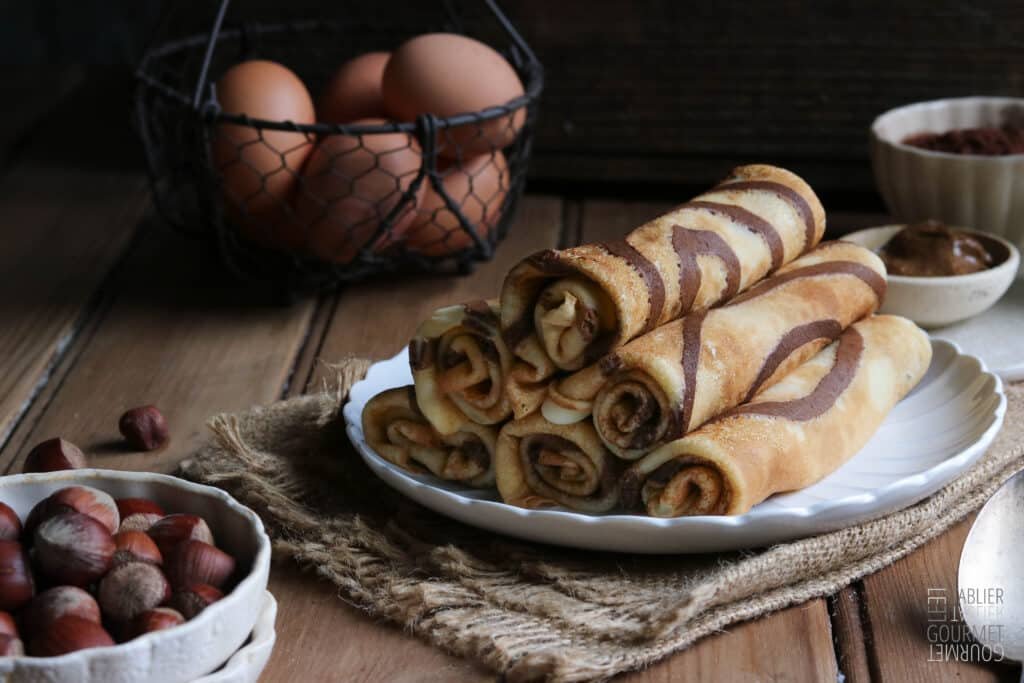 Des crêpes zébrées au cacao et à la noisettes qui sont roulées et mises en tas